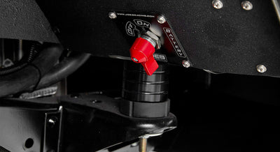Close-up of red battery disconnect switch mounted on black surface beneath Classic Ford Bronco dashboard