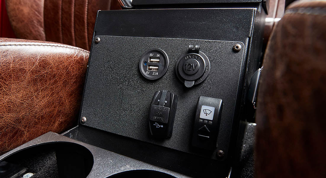 Close-up of black control panel with USB, 12V sockets, and switches inside Classic Ford Bronco