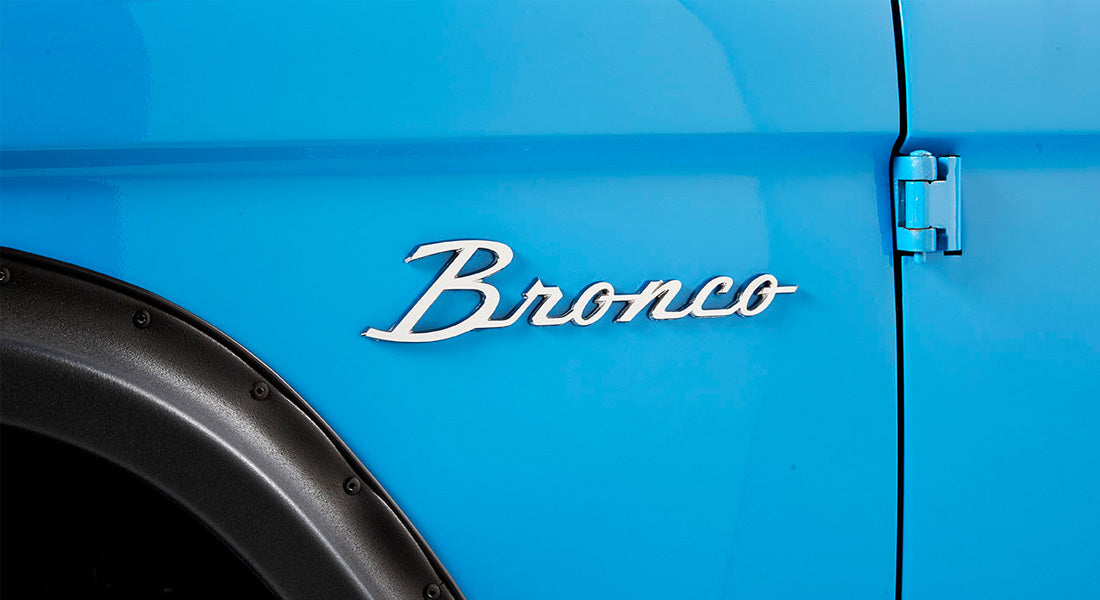 Classic Ford Bronco emblem on the blue exterior side panel near door hinges and black fender flare