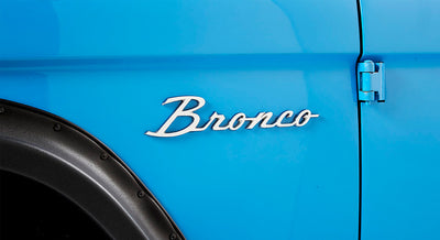 Classic Ford Bronco emblem on the blue exterior side panel near door hinges and black fender flare
