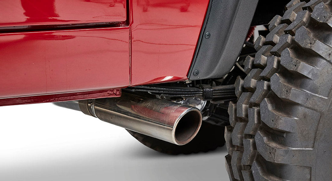 Close-up of the exhaust pipe and rear tire of a red Classic Ford Bronco
