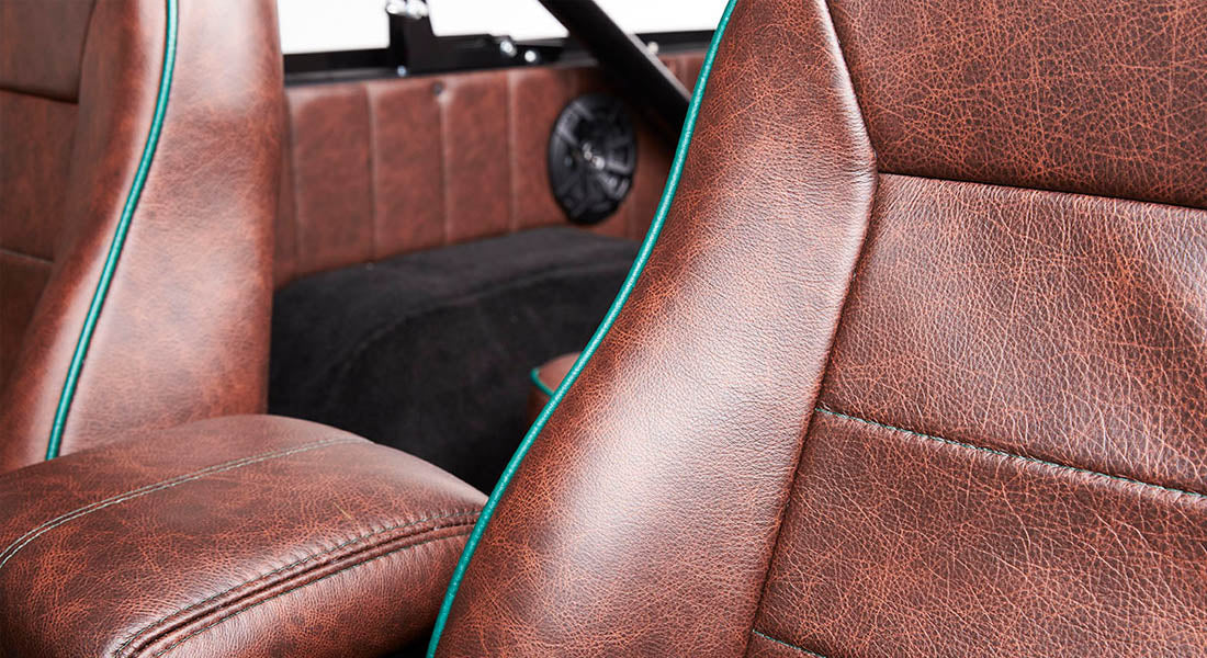 Brown leather seats with teal piping inside Classic Ford Bronco with rear speaker in background