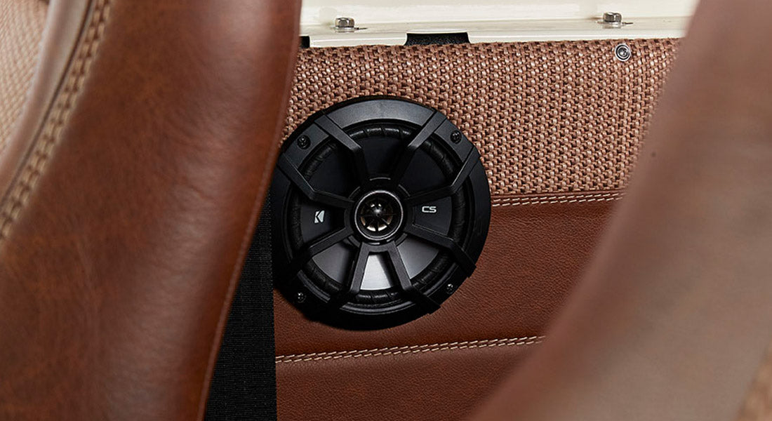 Black circular speaker mounted in brown leather and fabric interior panel