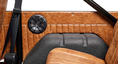 Interior side panel of Classic Ford Bronco with a mounted black speaker and brown leather upholstery.