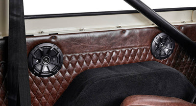 Two black round speakers embedded in brown diamond-stitched upholstery inside Classic Ford Bronco