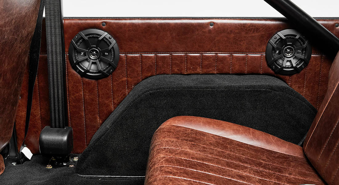 Two black speakers mounted inside Classic Ford Bronco with brown leather interior