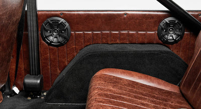 Two black speakers mounted inside Classic Ford Bronco with brown leather interior