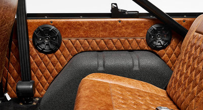 Two black speakers inside brown quilted leather panel in Classic Ford Bronco interior
