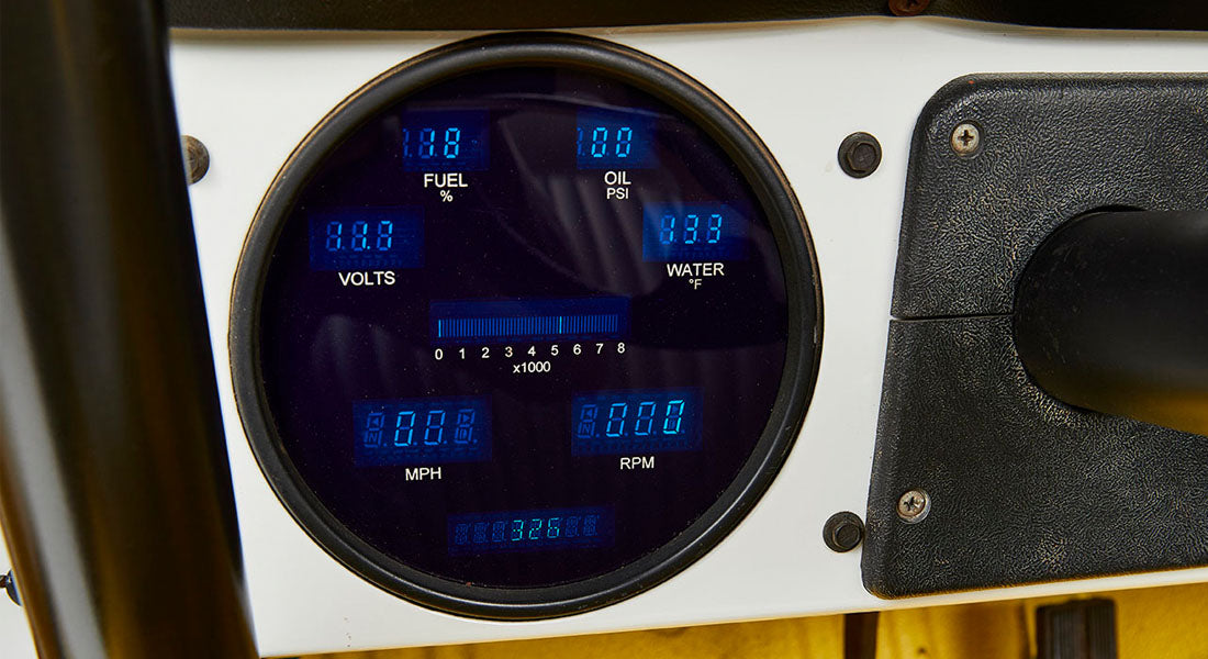 Round vehicle gauge cluster with digital blue display showing fuel, oil, volts, water, speed, and RPM