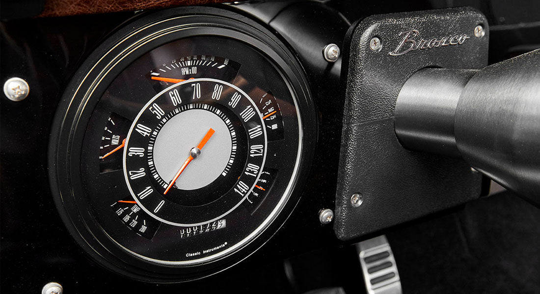 Classic Ford Bronco speedometer with black dial, white numbers, and orange needle