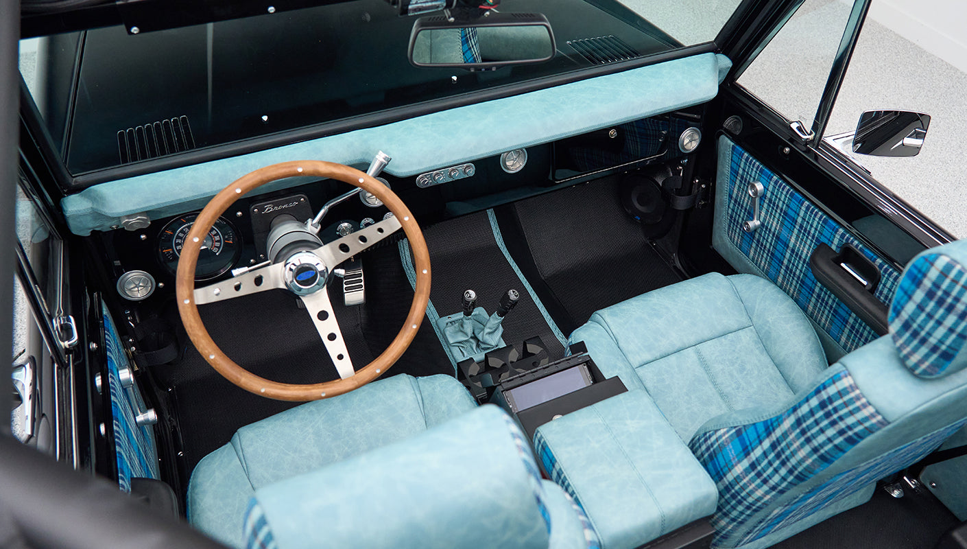 Overhead view of Classic Ford Bronco interior with wooden steering wheel and blue plaid seats
