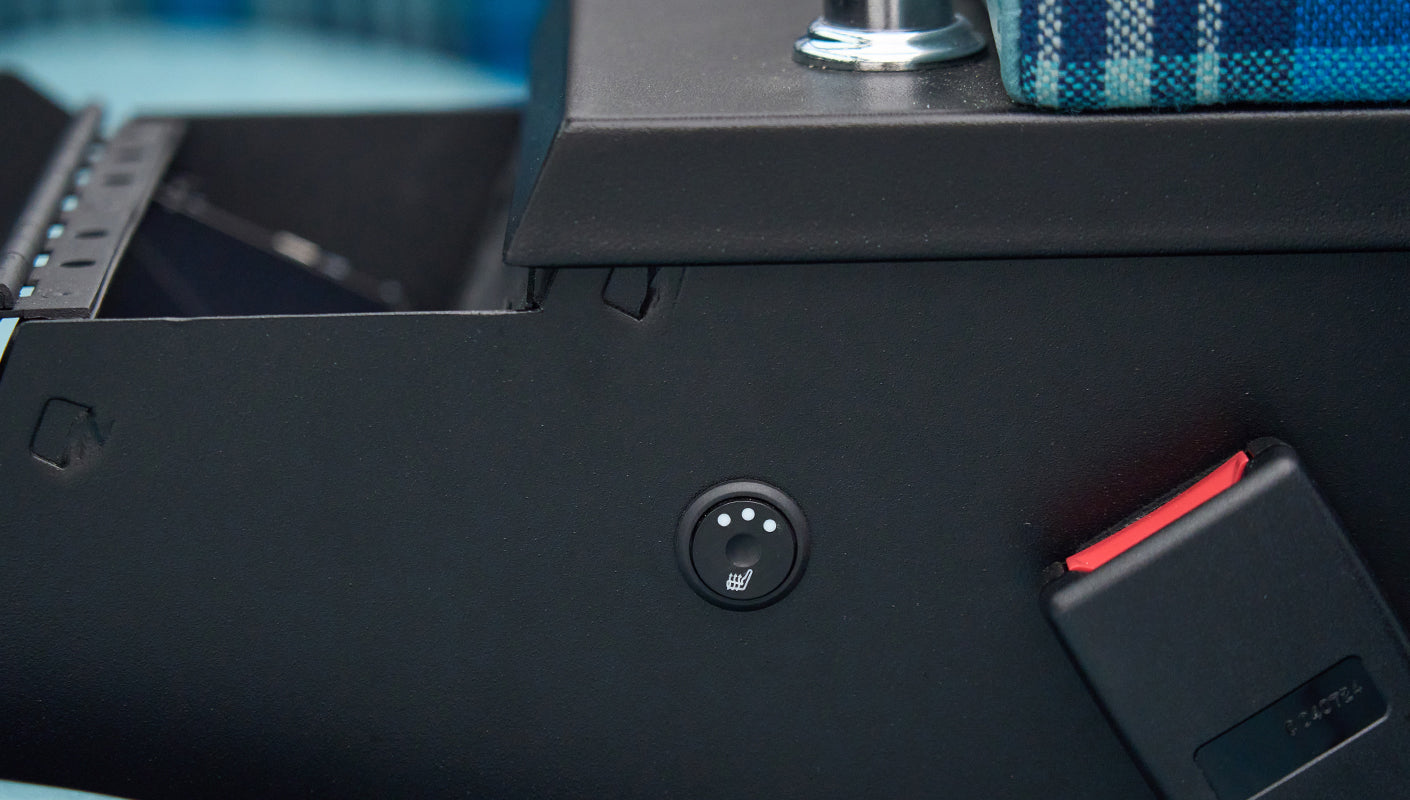 Detail of seat heating control button and red seatbelt buckle in Classic Ford Bronco interior