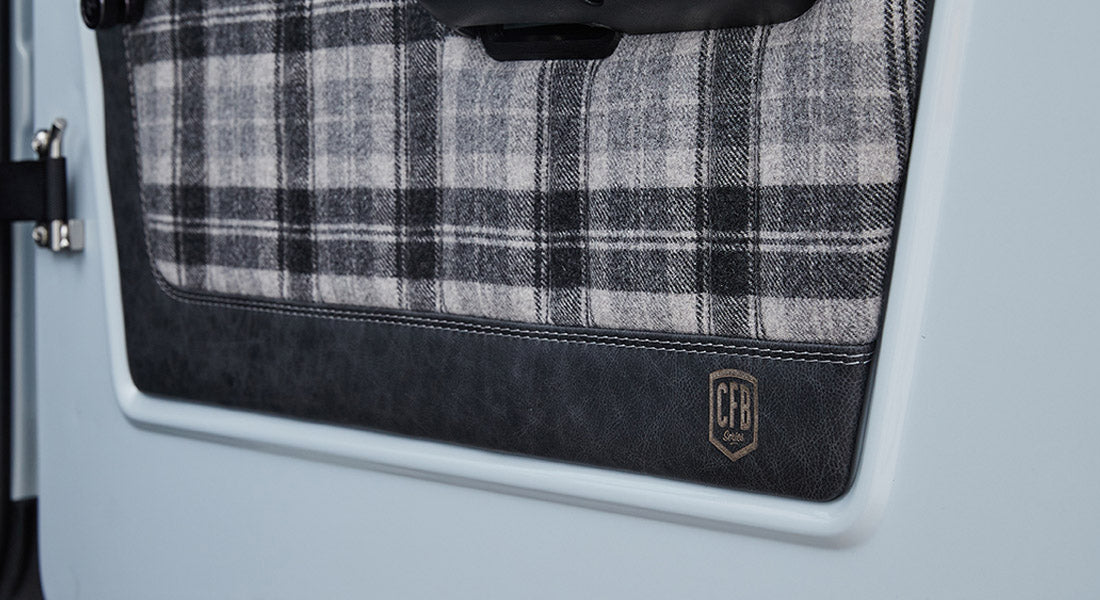 Plaid fabric and leather panel with CFB logo on the door of a Classic Ford Bronco
