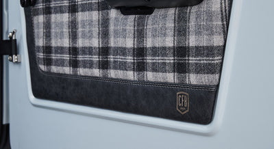 Plaid fabric and leather panel with CFB logo on the door of a Classic Ford Bronco