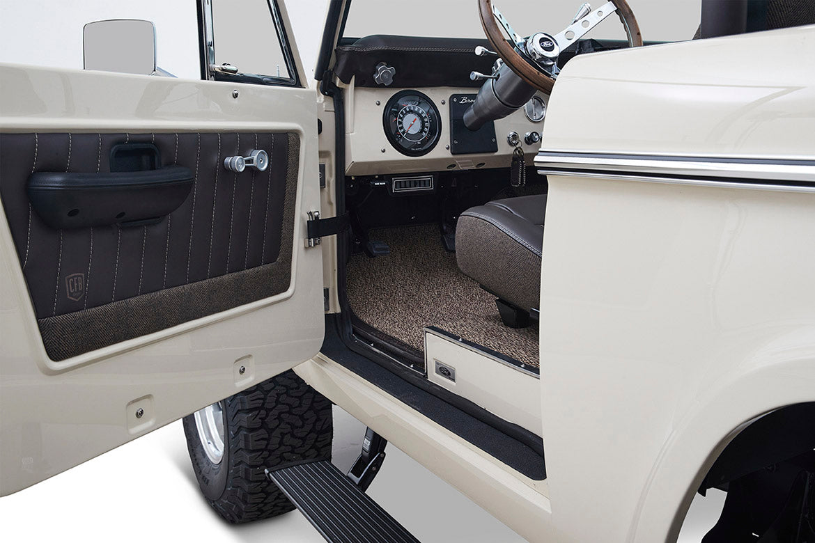 Open driver door showing brown padded interior door panel and seat inside Classic Ford Bronco