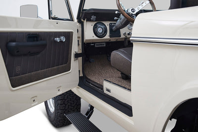 Open driver door showing brown padded interior door panel and seat inside Classic Ford Bronco