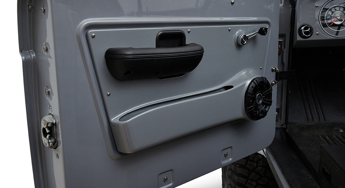 Interior side of Classic Ford Bronco door with black speaker, door handle and grey panel