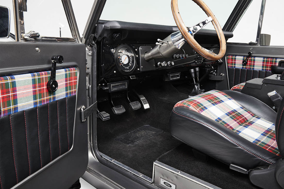 Classic Ford Bronco interior door panel with plaid fabric and manual window crank
