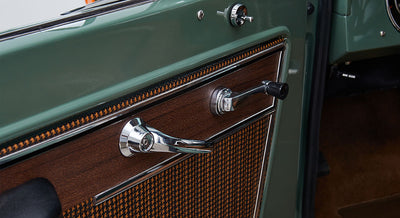 Door panel of Classic Ford Bronco showing wood-grain and houndstooth fabric with chrome handles