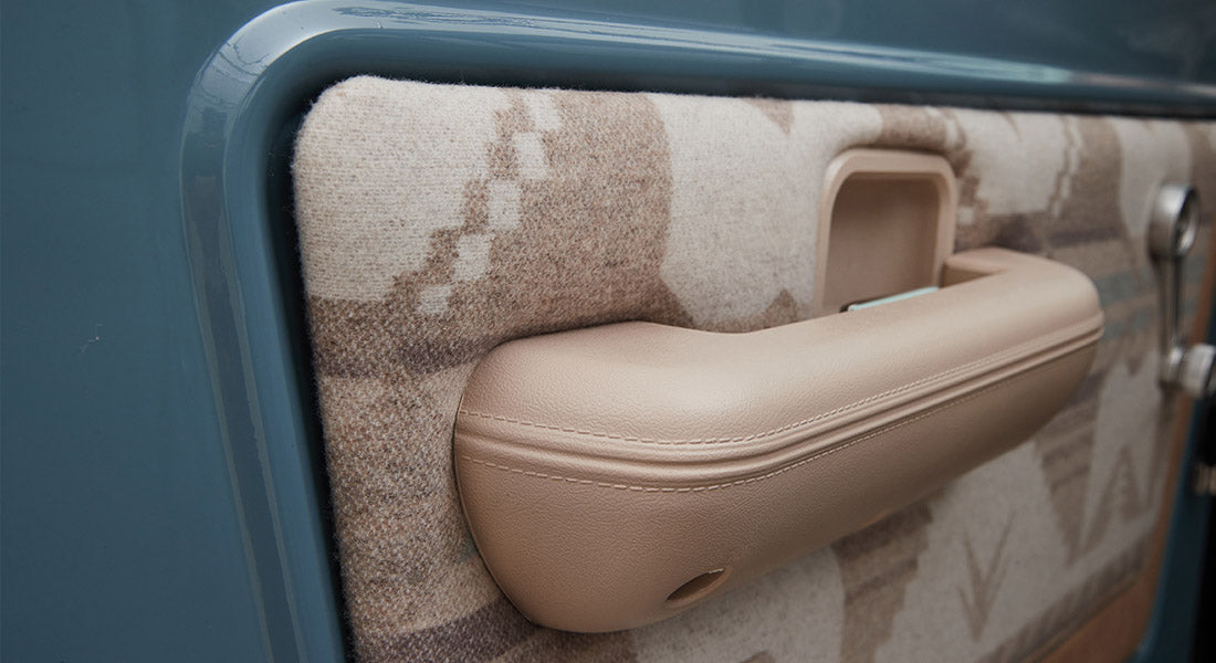 Interior door panel with patterned fabric and beige armrest of Classic Ford Bronco