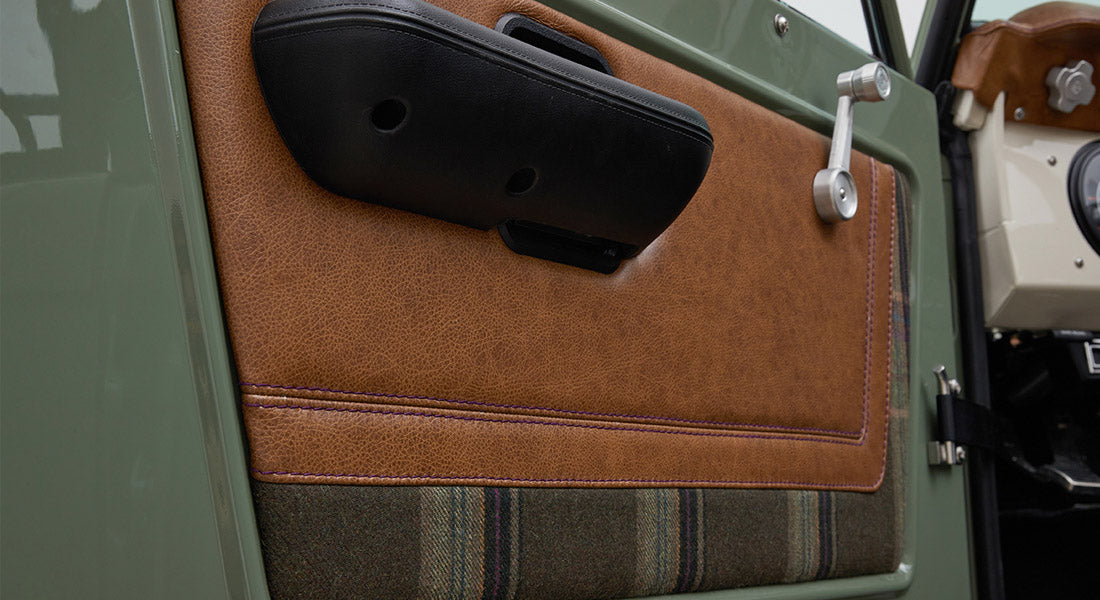 Interior door panel with brown leather, fabric insert, and black armrest of Classic Ford Bronco