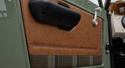 Interior door panel with brown leather, fabric insert, and black armrest of Classic Ford Bronco