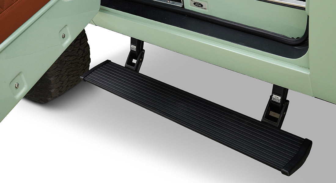 Retractable black door step extended from the mint green Classic Ford Bronco with visible tire and door edge.