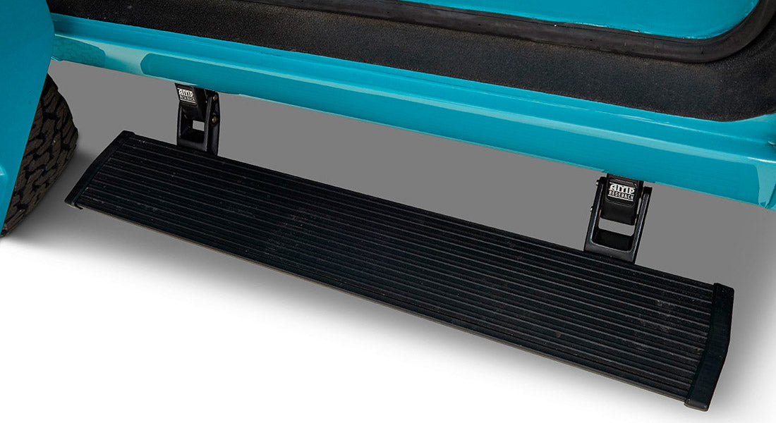 Black metal door step attached below aqua blue vehicle door on a white background