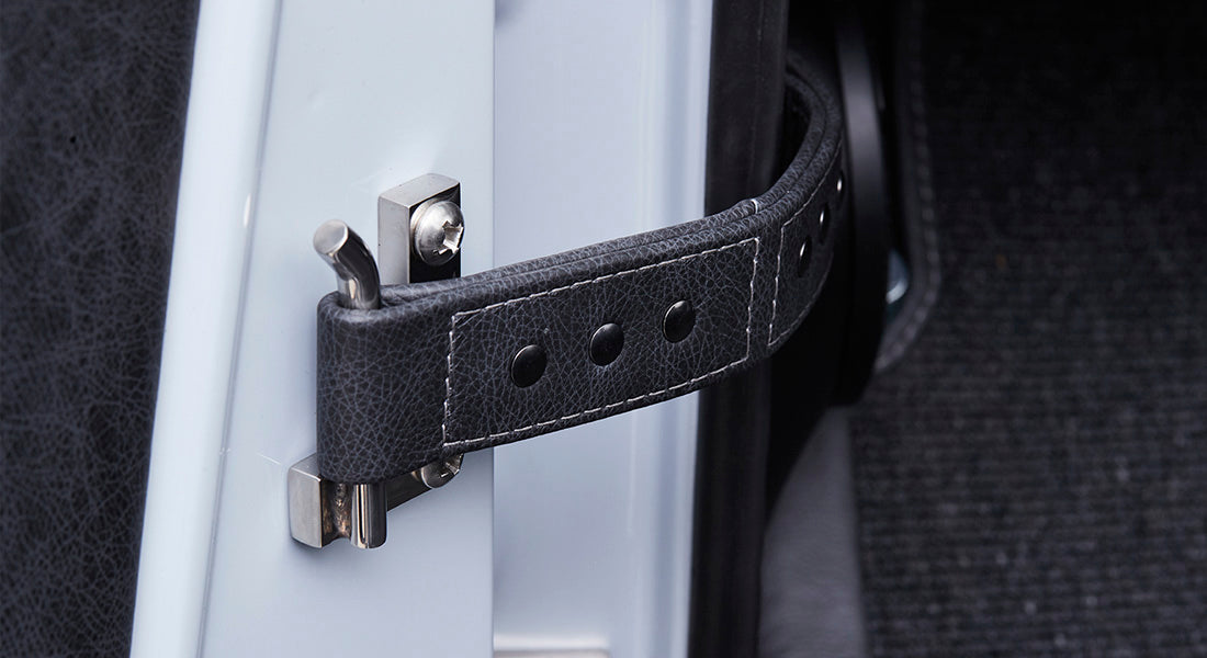 Vehicle door strap made from black stitched material attached to painted door frame