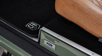 Black floor mats with white CFB Series logo and tan leather seat base in Classic Ford Bronco