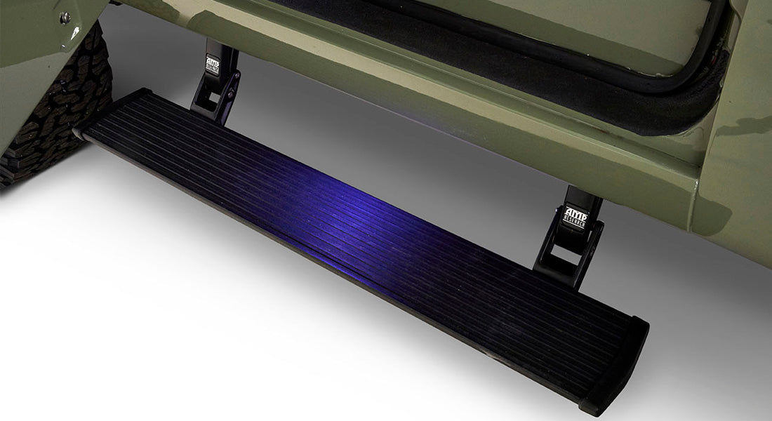 Black motorized running board extended below light green Classic Ford Bronco door