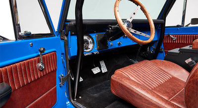 Classic Ford Bronco interior with blue door panels, wooden steering wheel, and driver's seat
