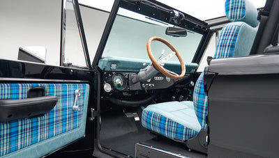 Classic Ford Bronco driver's side interior showing steering wheel and plaid seat