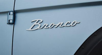 Silver Bronco emblem on light blue door panel of Classic Ford Bronco