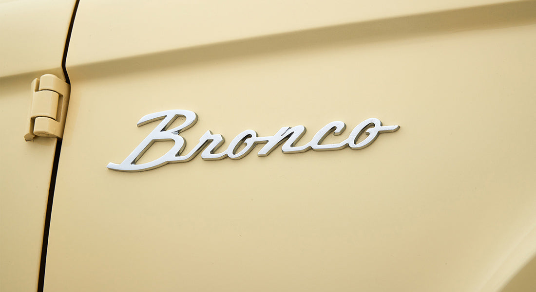 Chrome 'Bronco' emblem on pale yellow Classic Ford Bronco exterior door