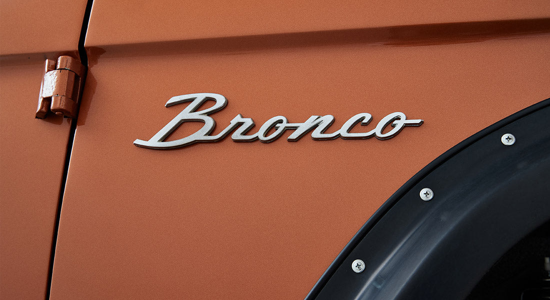 Close-up of Classic Ford Bronco orange exterior with silver Bronco emblem