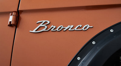 Close-up of Classic Ford Bronco orange exterior with silver Bronco emblem