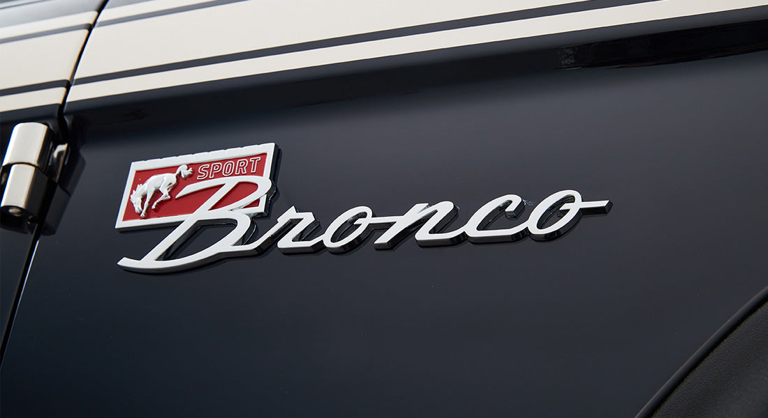 Close-up of Classic Ford Bronco chrome emblem on glossy black vehicle body