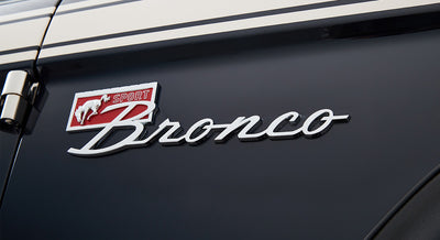 Close-up of Classic Ford Bronco chrome emblem on glossy black vehicle body