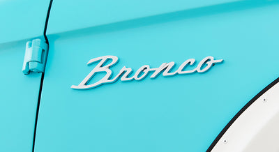 Silver Bronco emblem mounted on turquoise exterior door of Classic Ford Bronco