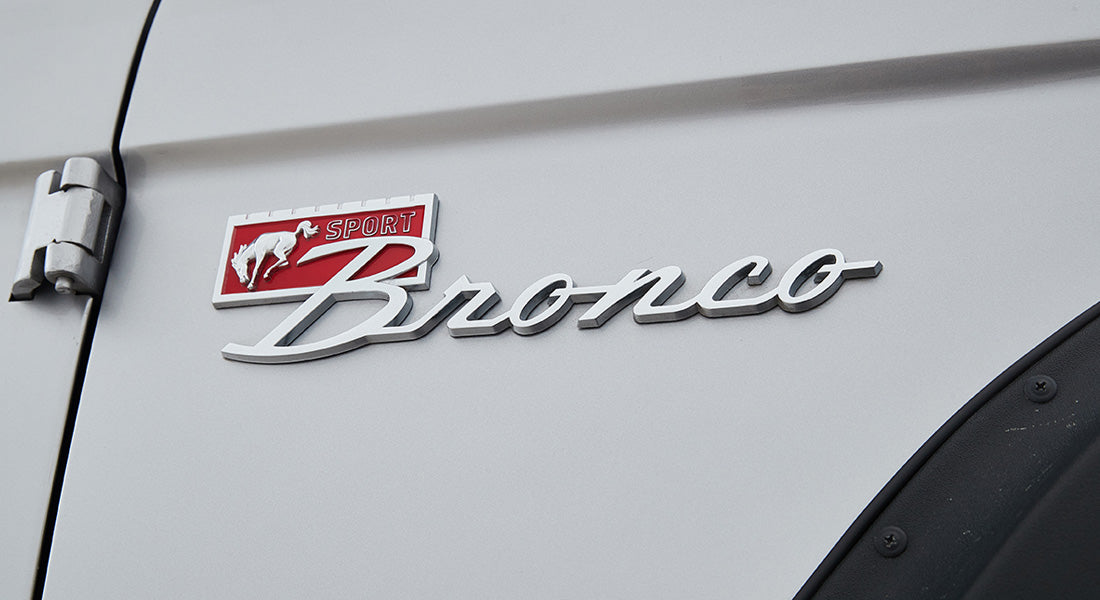 Close-up of silver Classic Ford Bronco side emblem with red Sport logo and running horse