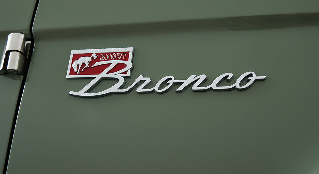 Classic Ford Bronco emblem on green painted vehicle exterior panel