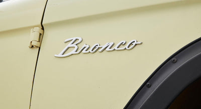 Close-up of silver Bronco emblem on cream colored vehicle door panel