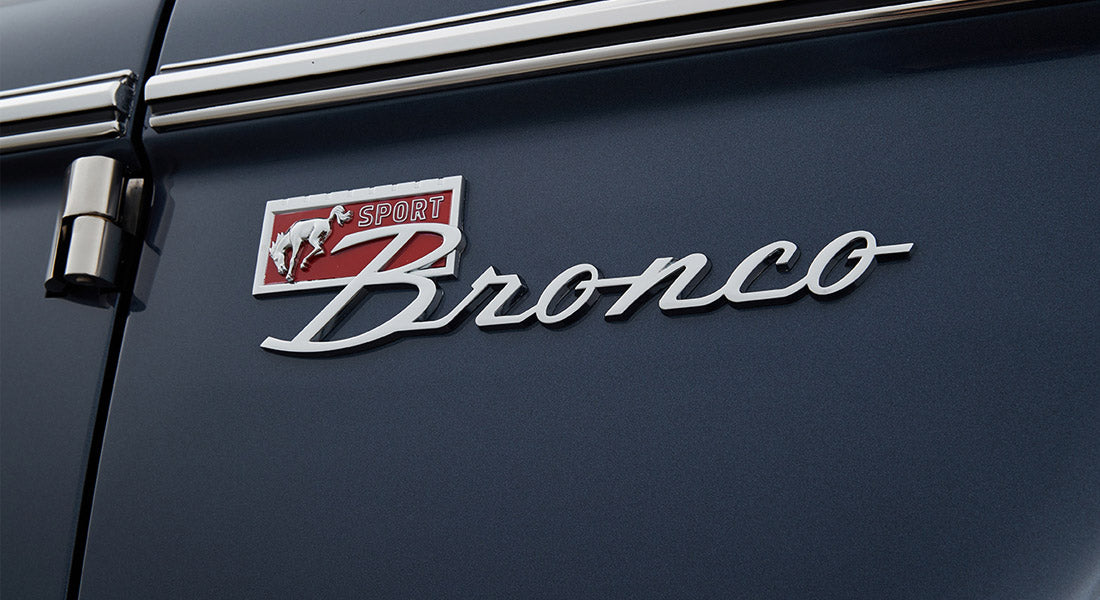 Chrome Classic Ford Bronco emblem with red sport logo on dark blue vehicle body