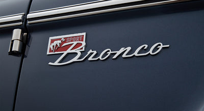 Chrome Classic Ford Bronco emblem with red sport logo on dark blue vehicle body