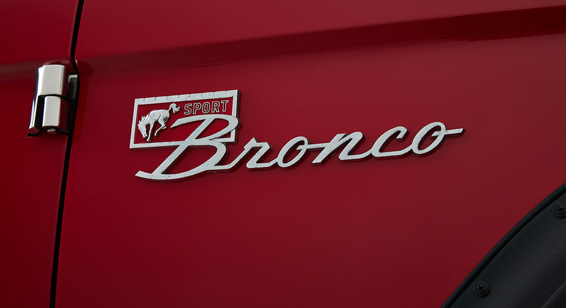 Close-up of chrome Classic Ford Bronco emblem on red vehicle body