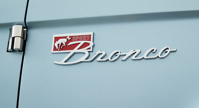 Chrome Sport Bronco emblem with a red background on a light blue vehicle door