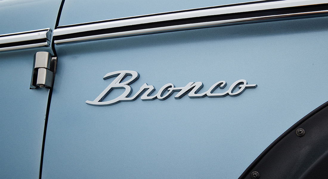 Chrome Classic Ford Bronco emblem mounted on light blue vehicle door