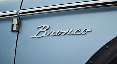 Chrome Classic Ford Bronco emblem mounted on light blue vehicle door