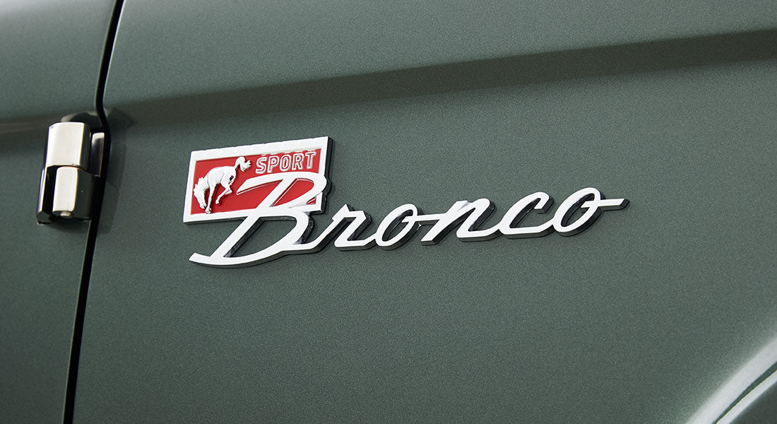 Classic Ford Bronco Sport emblem with white script and red background on green door